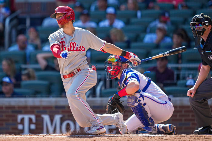 Trea Turner finishes his swing, with his bat behind him and one hand out